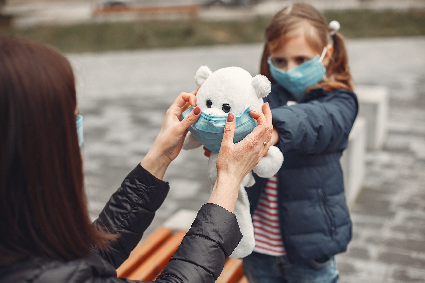 Woman in a disposable mask is teaching her child to wear a respi